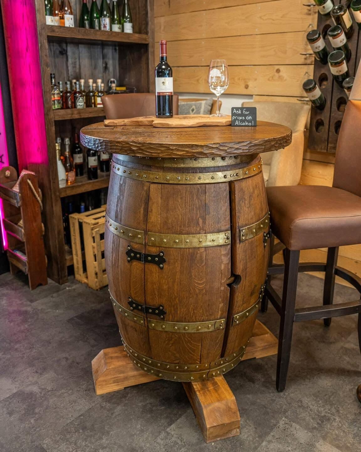 Standing table made from an oak barrel with brass bands and a hand-hewn top, a wine bottle and a glass on it